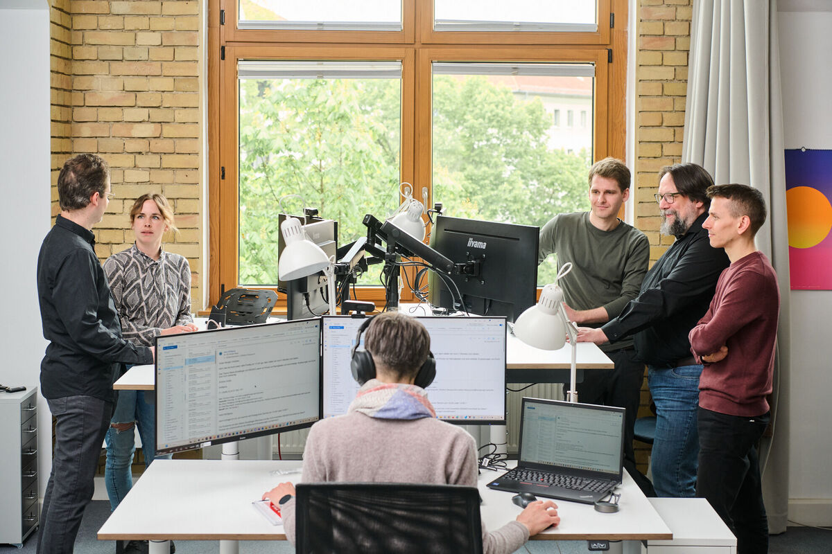 CMS-Entwicklung im Team – kollaborative Planung und Umsetzung Entwicklungsteam arbeitet in Meetings und an Rechnern an maßgeschneiderten CMS-Lösungen für effizientes Content Publishing