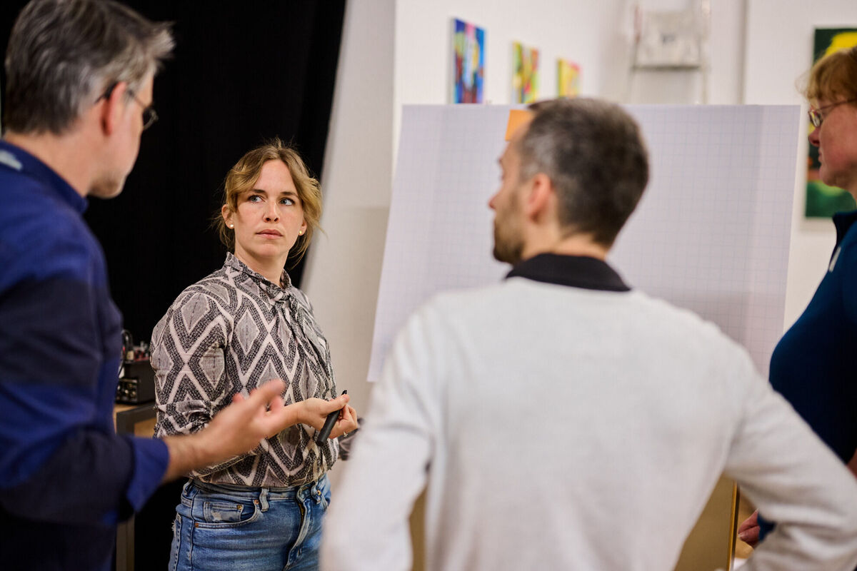 Strategieworkshop: Team-Mitglieder arbeiten am Leadmanagement der Immobilienplattform Team-Mitglieder im Strategie-Workshop zur digitalen Immobilienplattform, vor einem Flipchart mit Diagrammen und Notizen zum Leadmanagement.