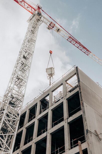 Rohbau eines Hochhauses mit Kran aus der Froschperspektive – Symbolbild für digitale Steuerung von Immobilienprojekten über eine zentrale Plattform.