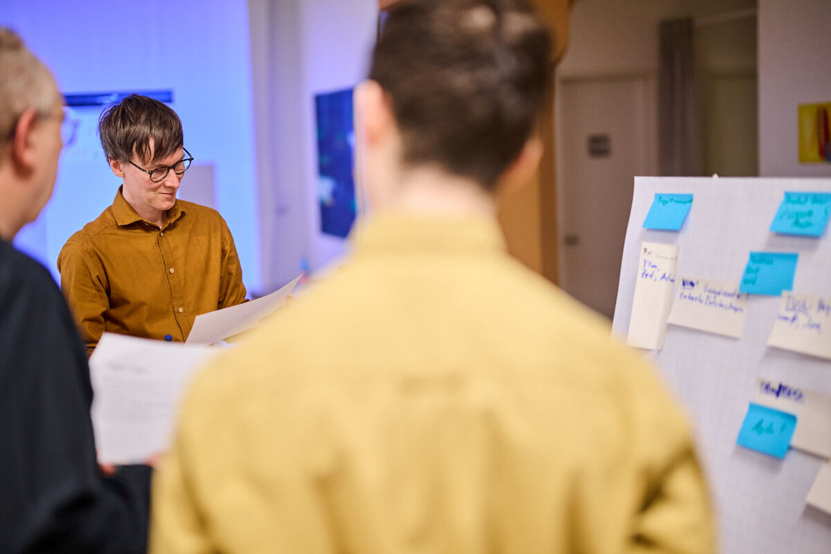 Entwickler-Team bei Workshop zur Planung eines individuellen Kundenportals Drei Entwickler im Workshop mit Flipchart und Unterlagen planen die Entwicklung eines individuellen Kundenportals