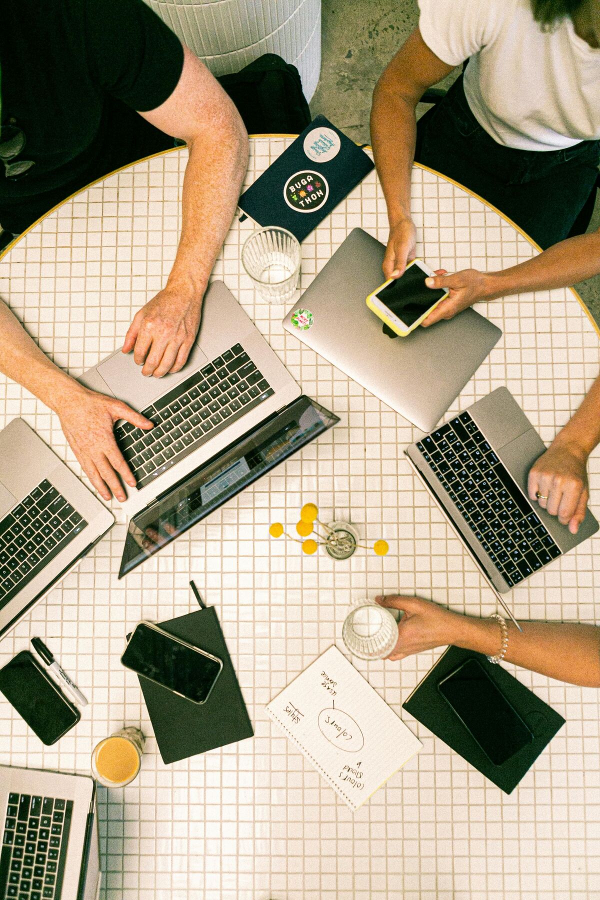 Mehrere Personen arbeiten gemeinsam an einem Tisch mit Laptops und mobilen Endgeräten – symbolisch für teamübergreifende Zusammenarbeit bei der zentralen Pflege von Produktdaten mit einer PIM-Softwarelösung.